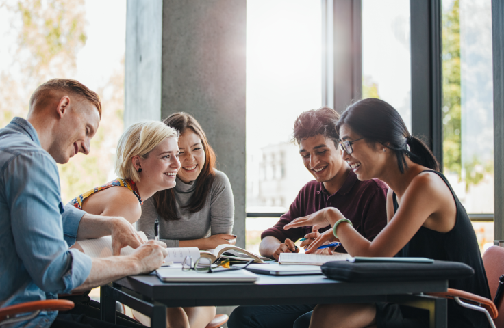 Students at a table chatting to each other and smiling